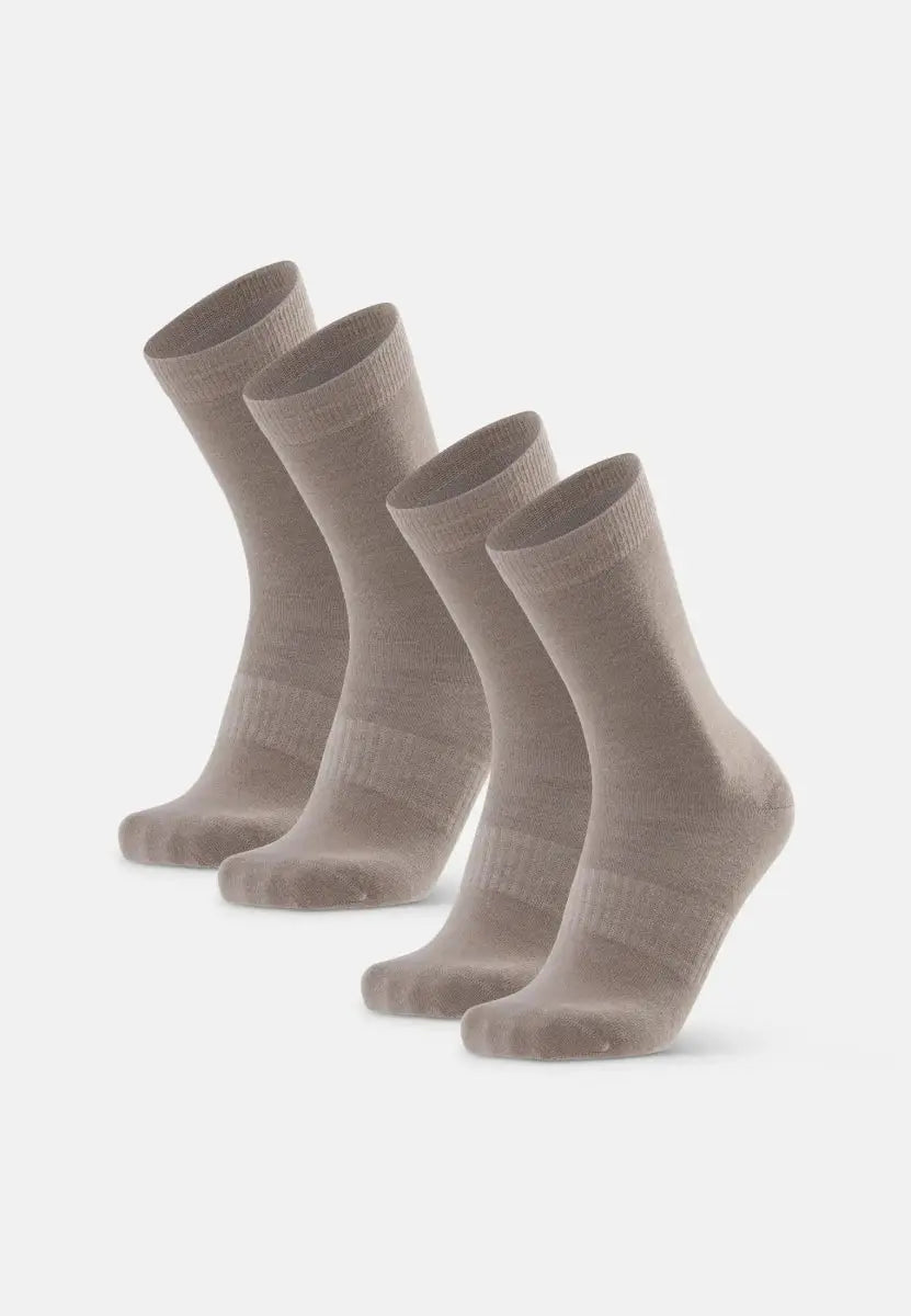 Four pairs of beige Merino wool hiking liner socks standing upright against a plain background.