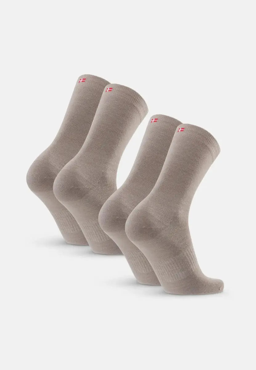 Four pairs of beige merino wool socks with red flag emblem, aligned in two rows.
