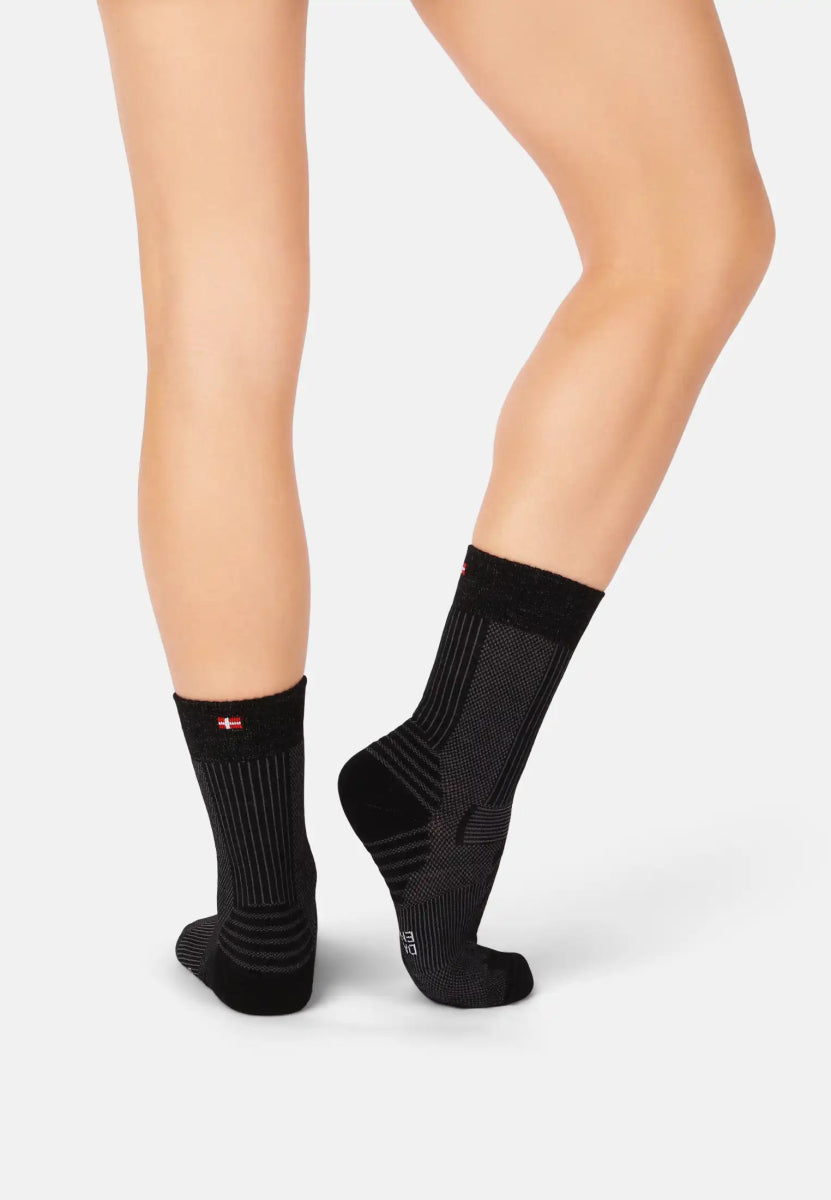 Black Merino wool hiking socks on legs, ribbed texture, red detail near top, suitable for hiking.