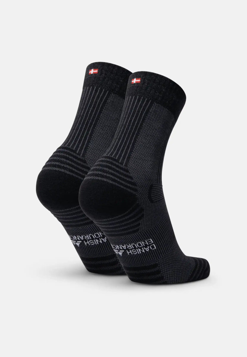 Black merino wool hiking socks with ribbed texture and "Danish Endurance" text on the sole.