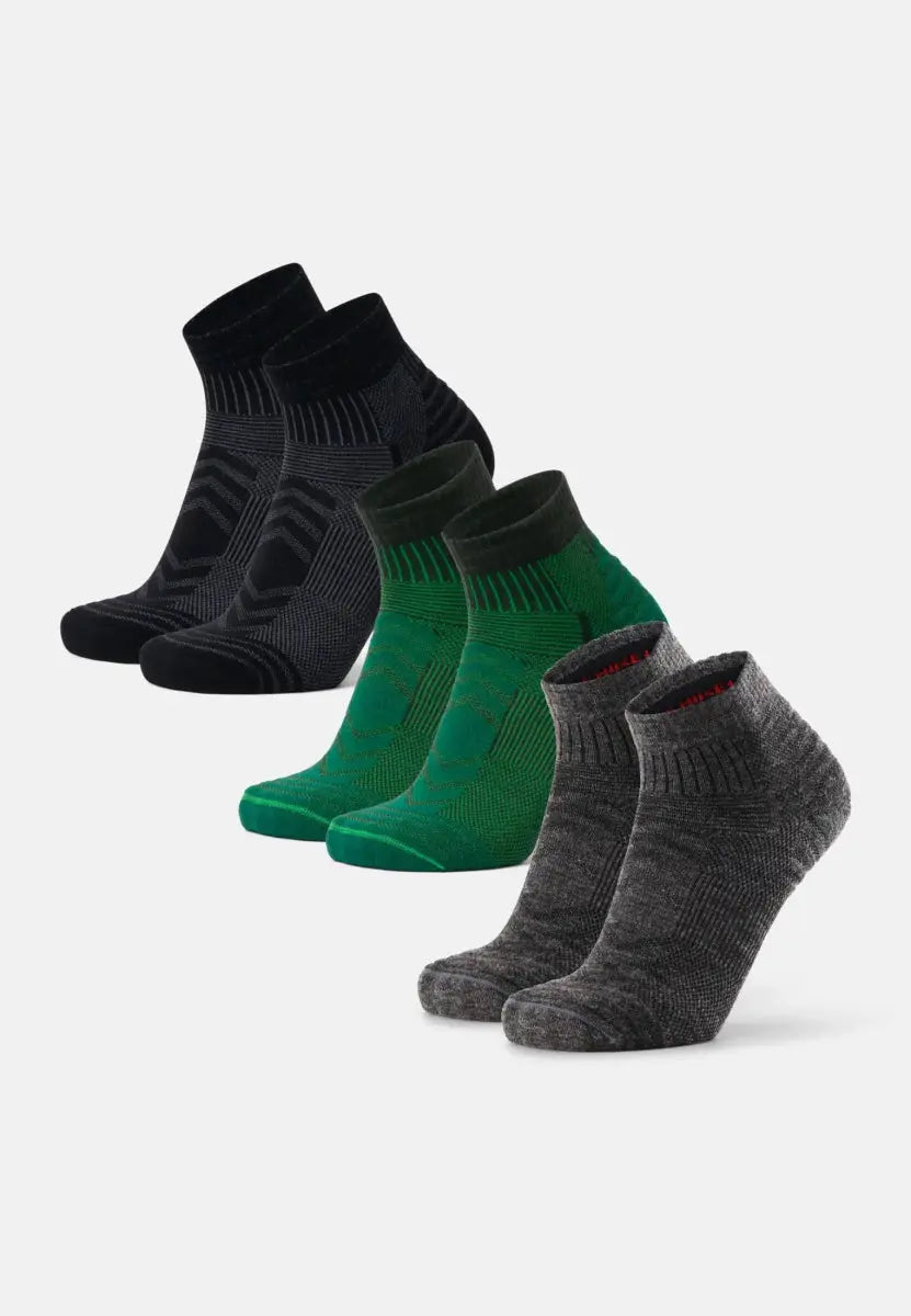 Three pairs of low-cut merino wool hiking socks in black, green, and gray, displayed in a row.