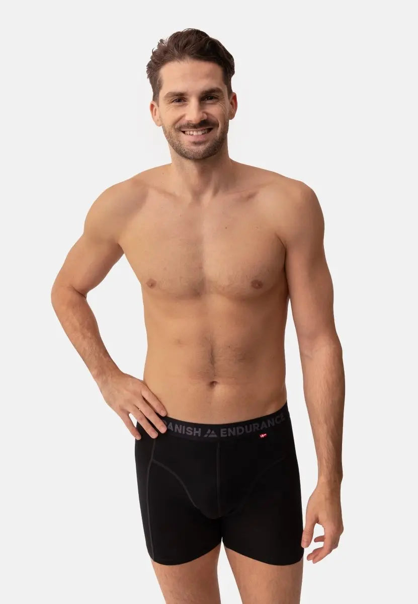 Man wearing black merino wool trunks with "DANISH ENDURANCE" on waistband, smiling, hands on hips.
