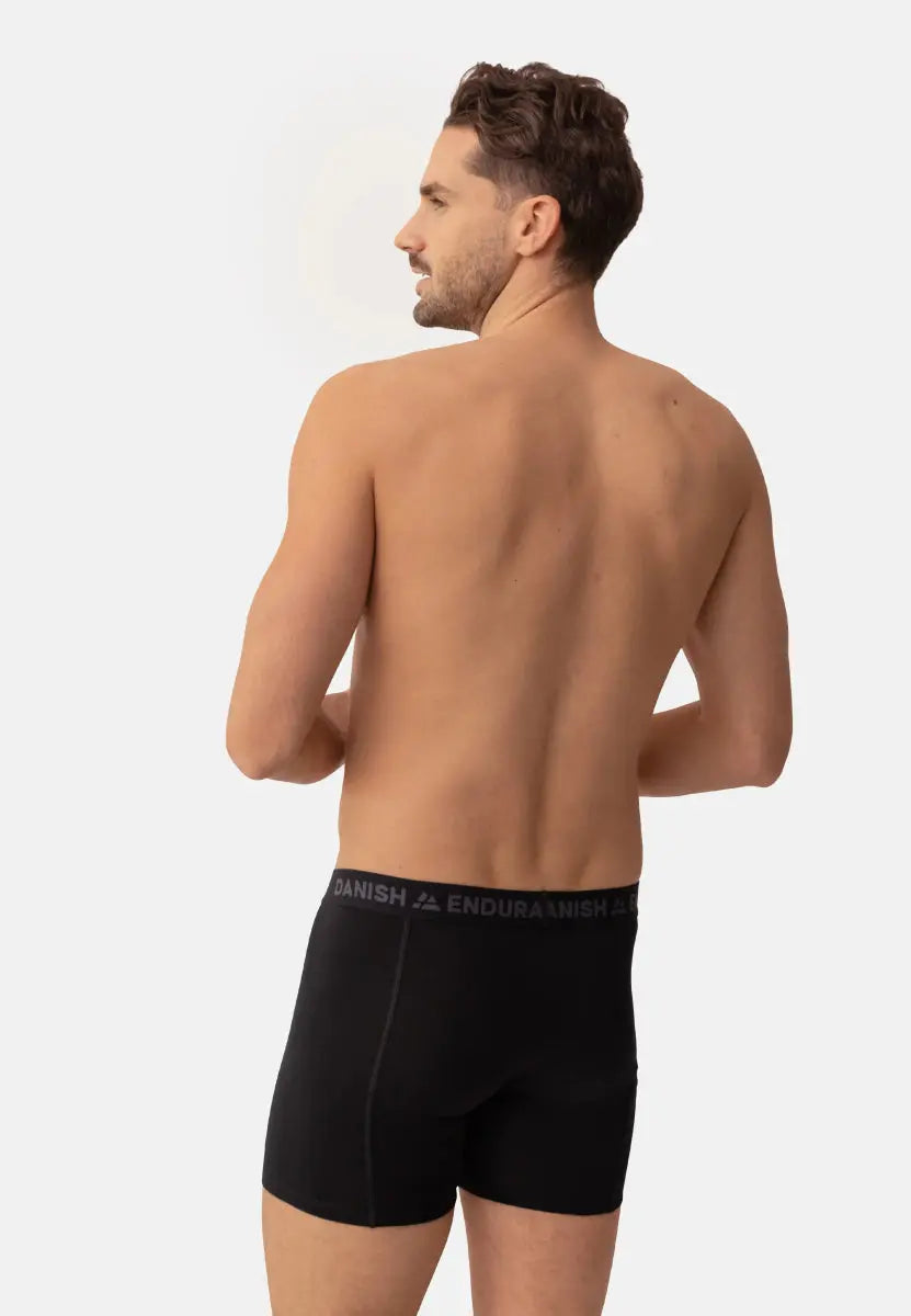 Man wearing black merino wool trunks, viewed from the back, waistband reads "DANISH ENDURANCE."