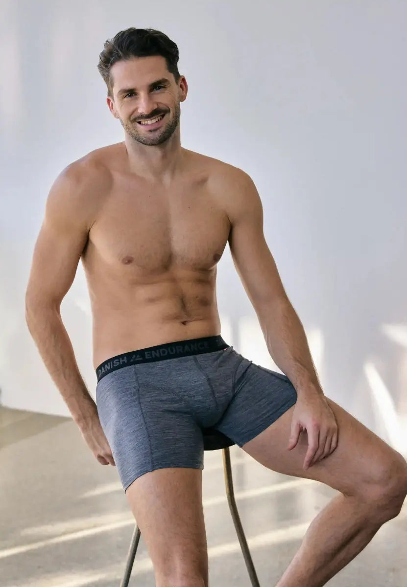 Man seated wearing gray merino wool trunks with "Danish Endurance" waistband, smiling in a bright room.