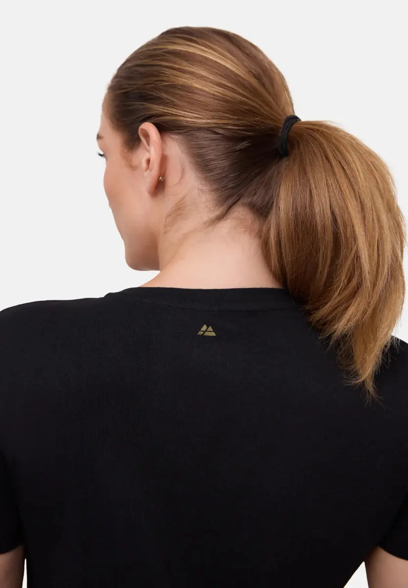 Back view of black crew neck t-shirt on woman with tied hair, small logo on upper back.