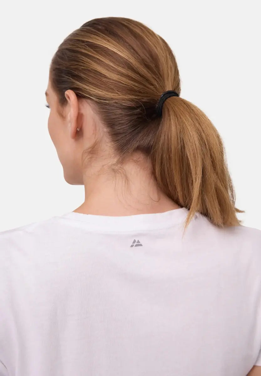 Woman with ponytail wearing white crew neck T-shirt, small logo on back.