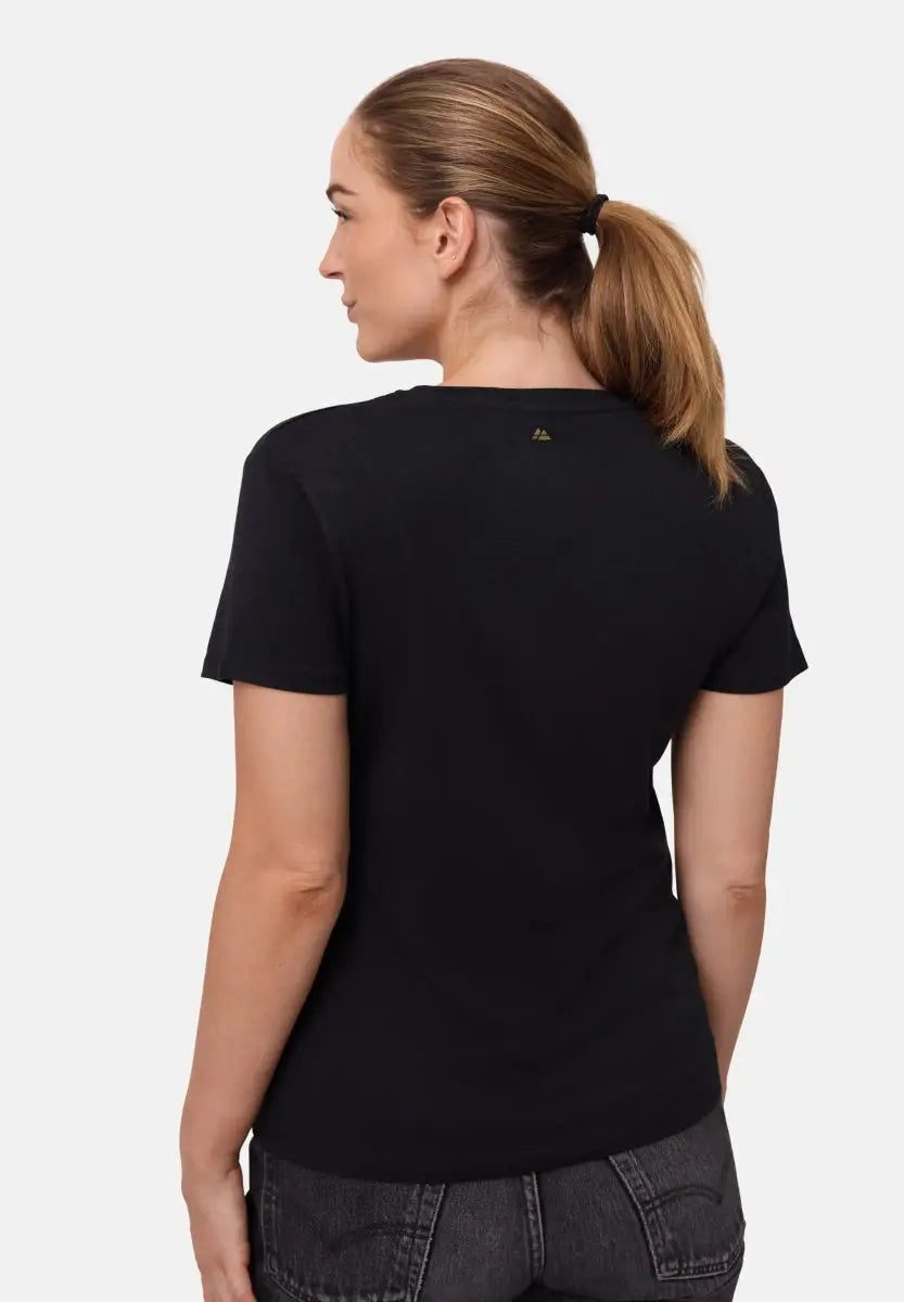 Woman in black crew neck t-shirt, dark jeans, ponytail; back view.