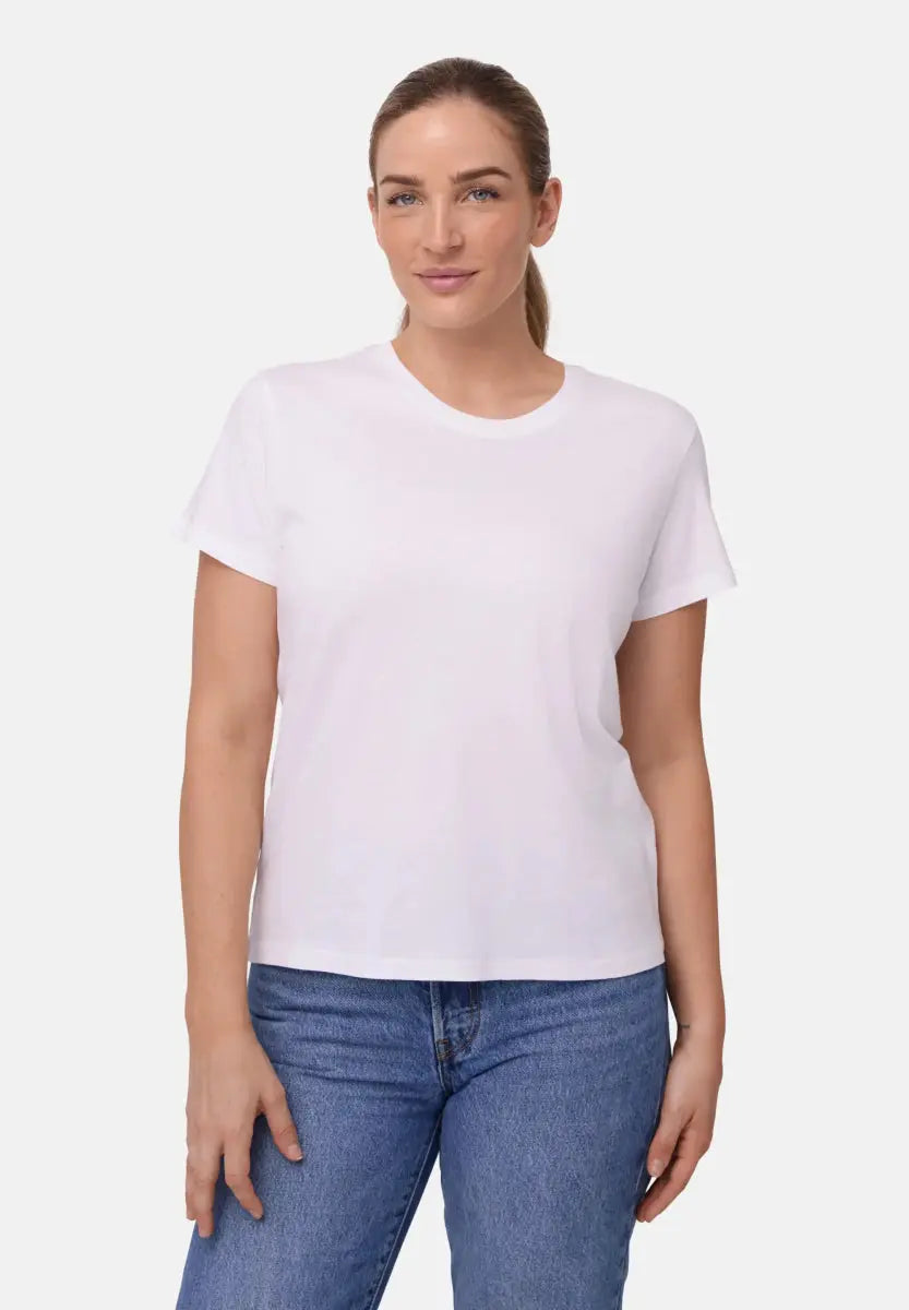 Woman in a white crew neck T-shirt and blue jeans, standing confidently against a plain background.