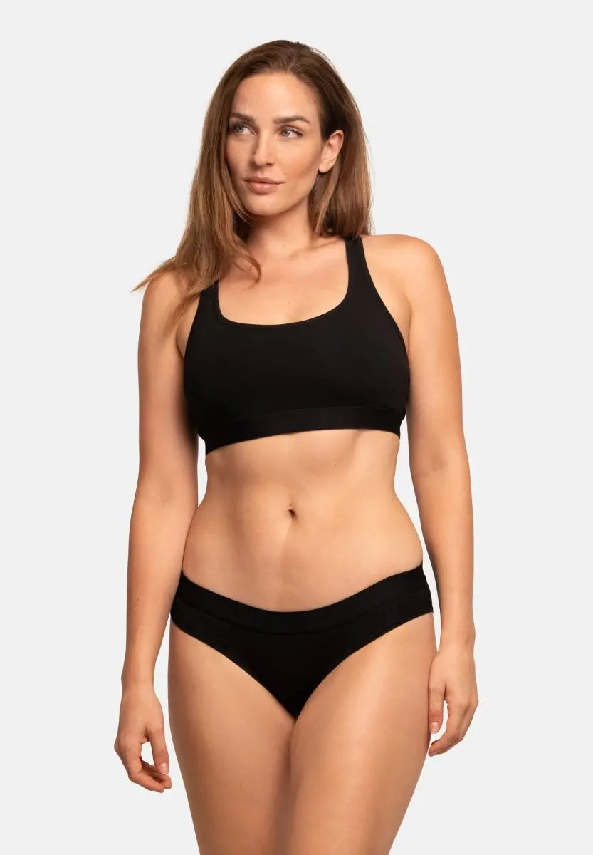 Person wearing black organic cotton bikini panties and matching top against a plain background.