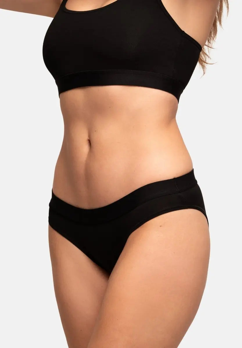Black bikini panties and top on a person, highlighting the soft organic cotton fabric.