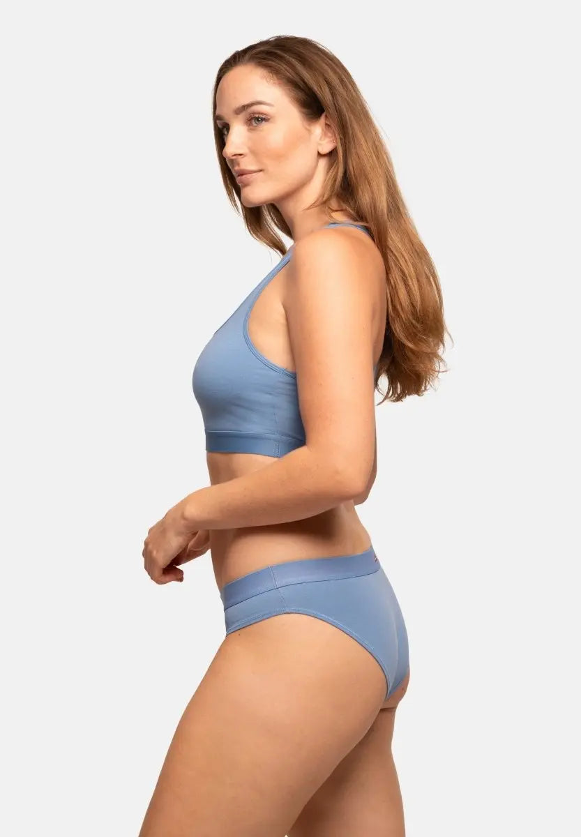 Person in light blue organic cotton bikini panties and top, side view, long hair flowing down.