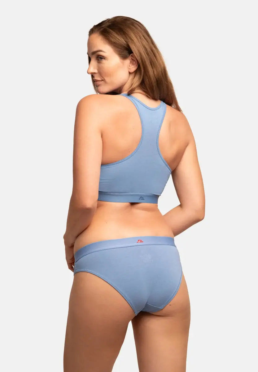 Woman in light blue racerback bralette and panties, viewed from the back.