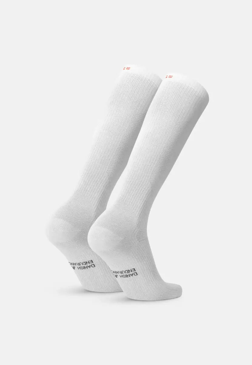 White knee-high organic cotton socks with text on the sole, displayed against a plain background.