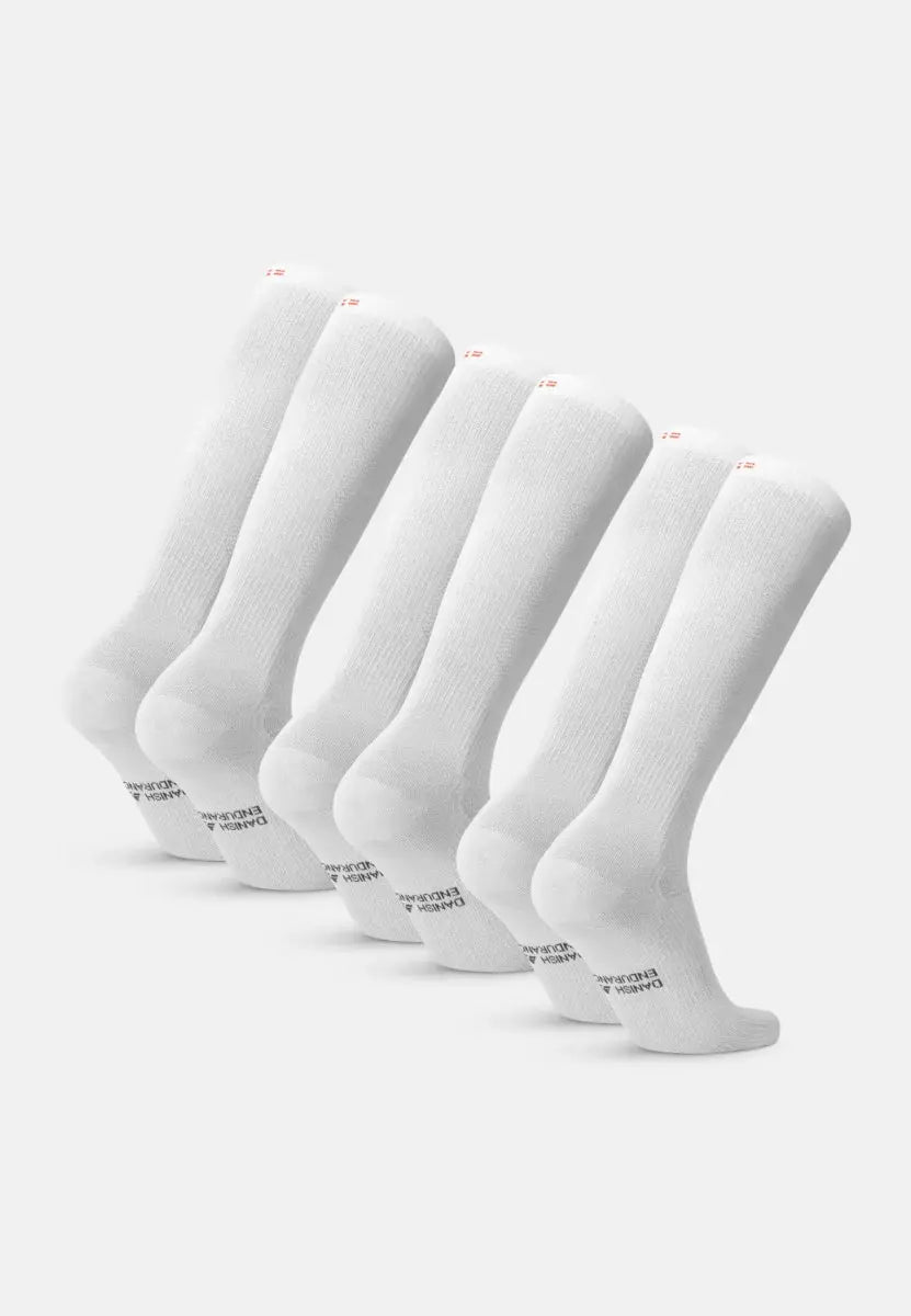Five pairs of white knee-high organic cotton socks aligned in a row on a plain background.