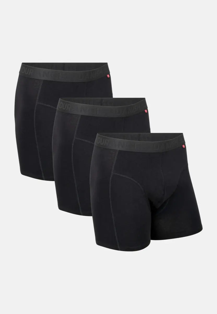Three black organic cotton trunks with logo waistband and small flag detail, side by side.
