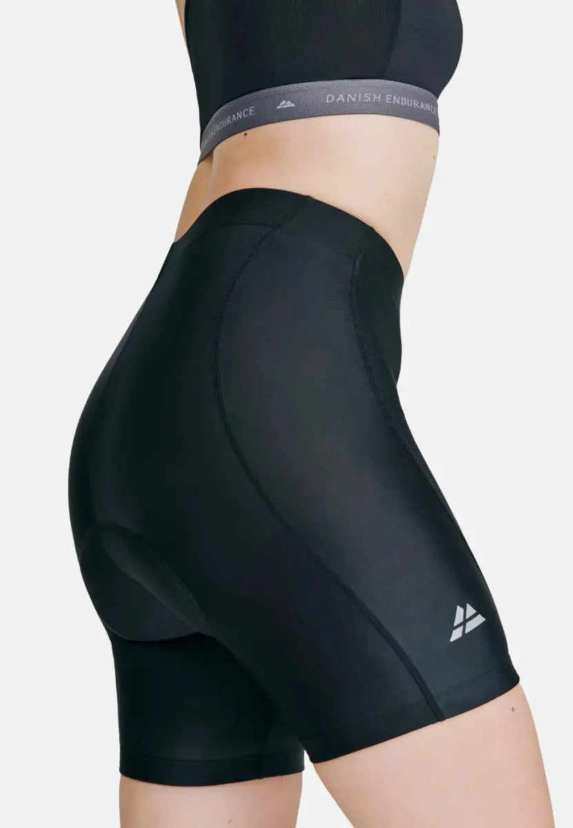 Black padded bike shorts with side logo, worn by a person, shown from the back.