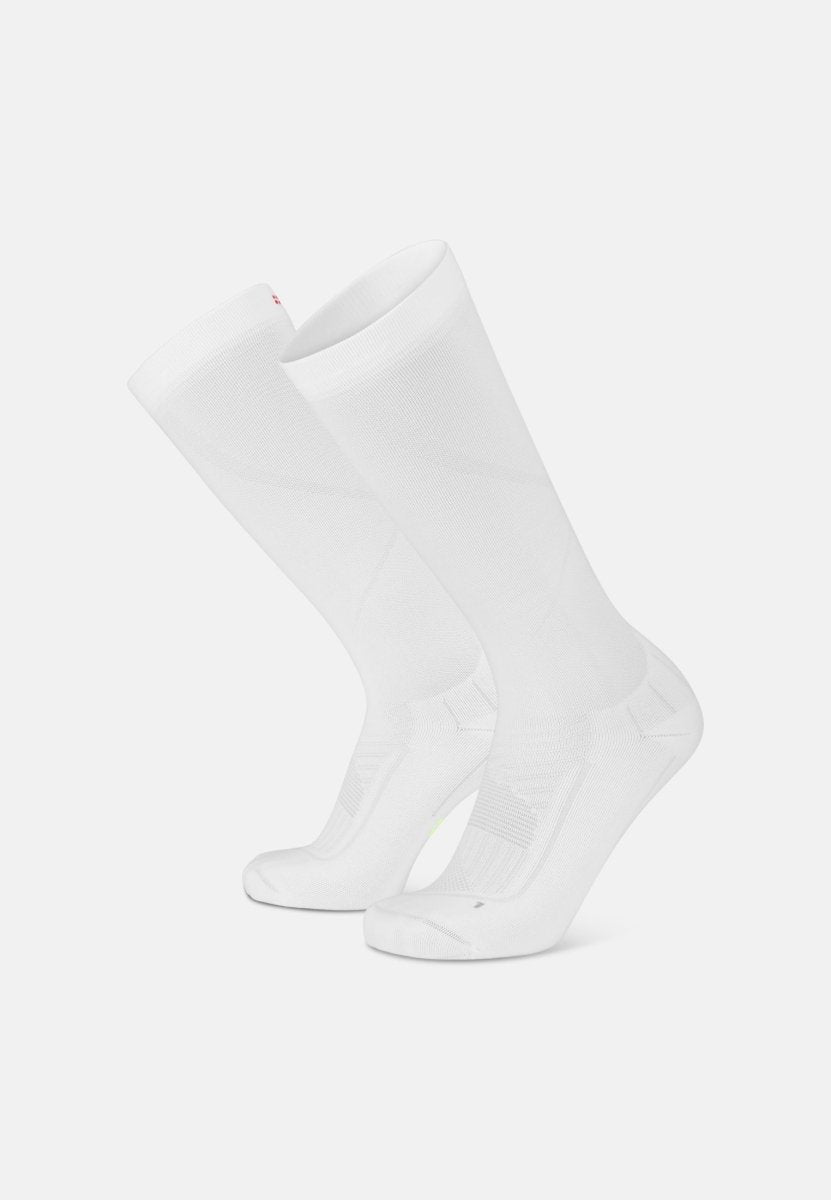 White knee-high compression socks with ribbed detailing, angled view, designed for sports performance.