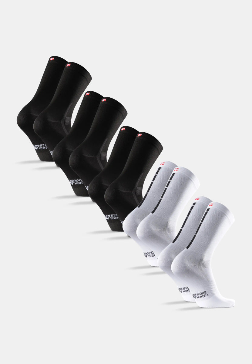 Eight cycling socks, four black and four white, each with a red logo on the cuff.