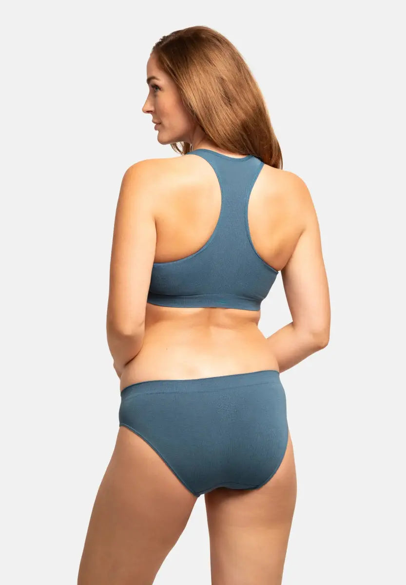 Woman in blue seamless bamboo bralette and briefs, viewed from the back, against a white background.