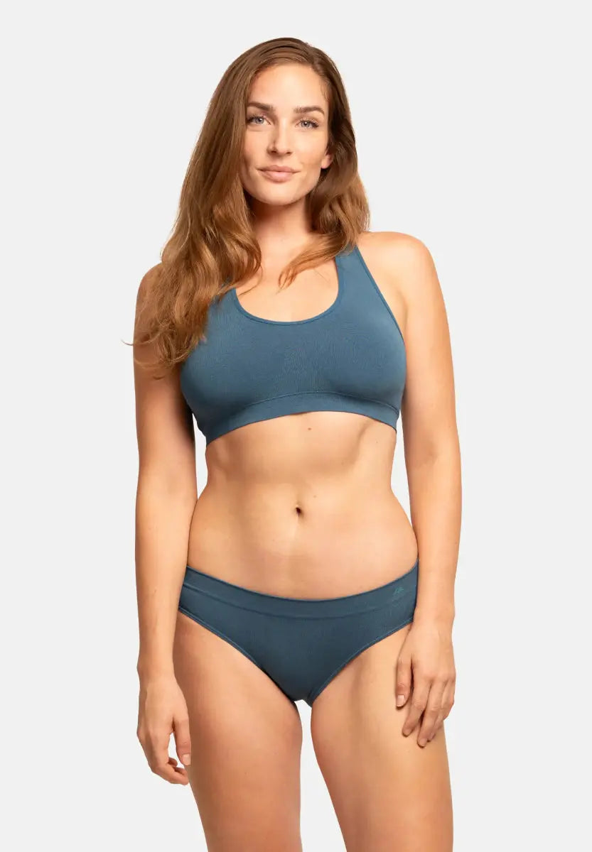 Woman in blue seamless bamboo bralette and briefs, standing against a white background.