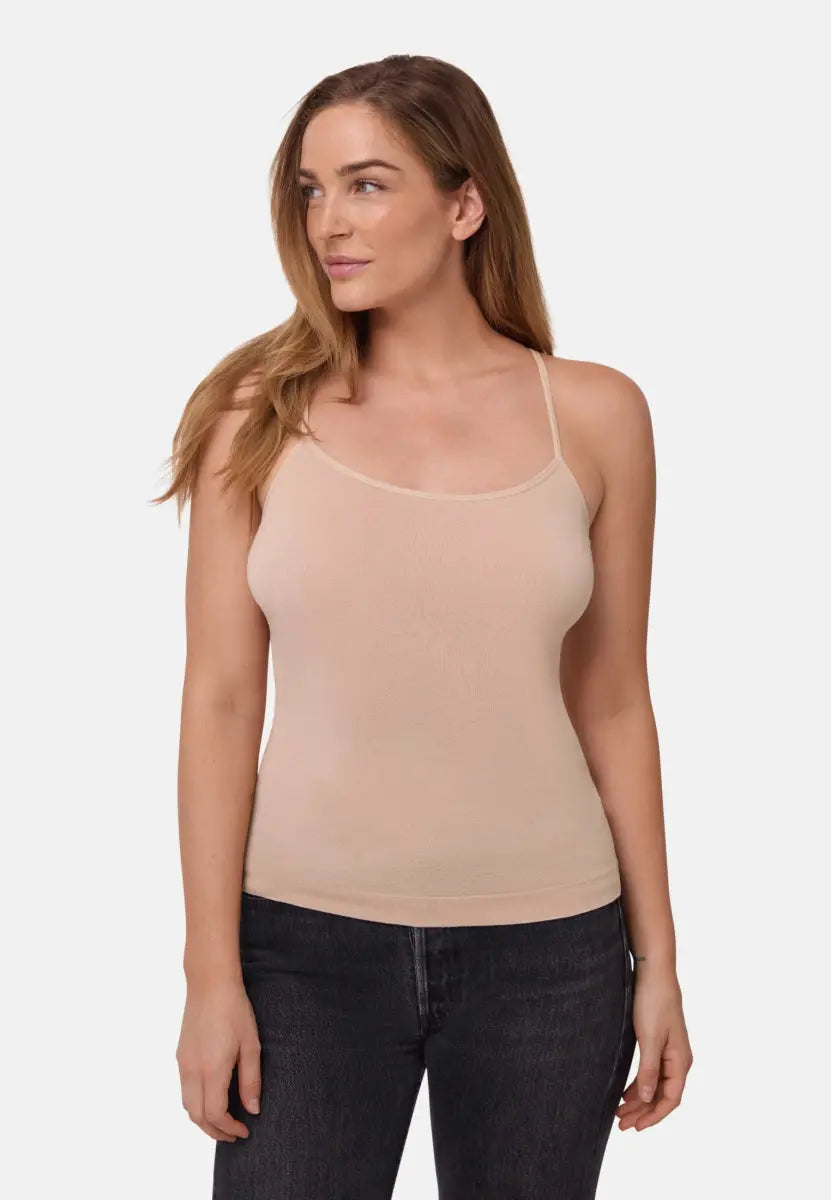 Woman wearing a neutral seamless bamboo singlet top with thin straps and dark jeans.