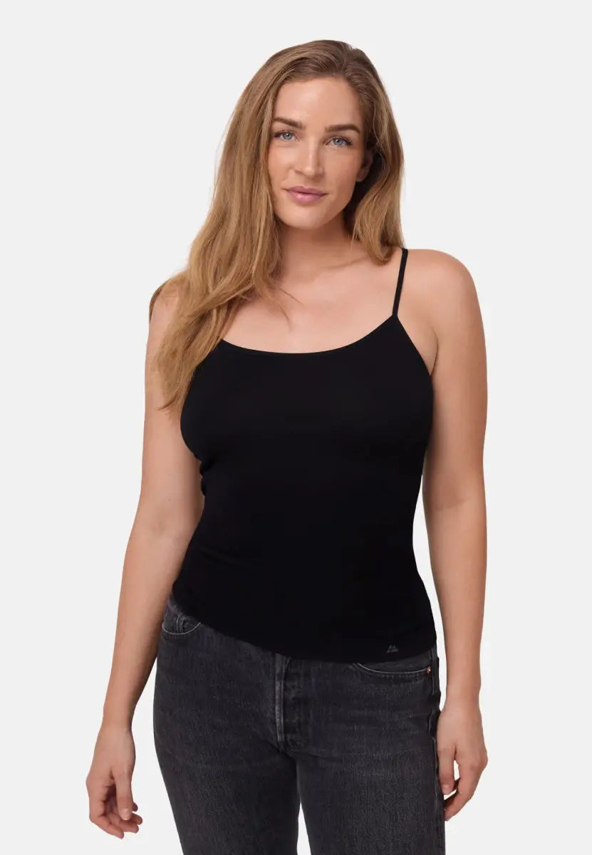 Woman in black seamless bamboo singlet top with thin straps, wearing dark jeans.