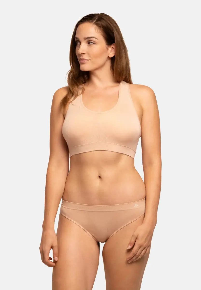Woman in nude seamless bamboo thong and matching top, looking to the side against a plain background.