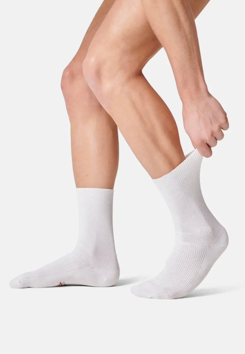 Person wearing white crew socks, adjusting one sock with hands, showing fit and texture.