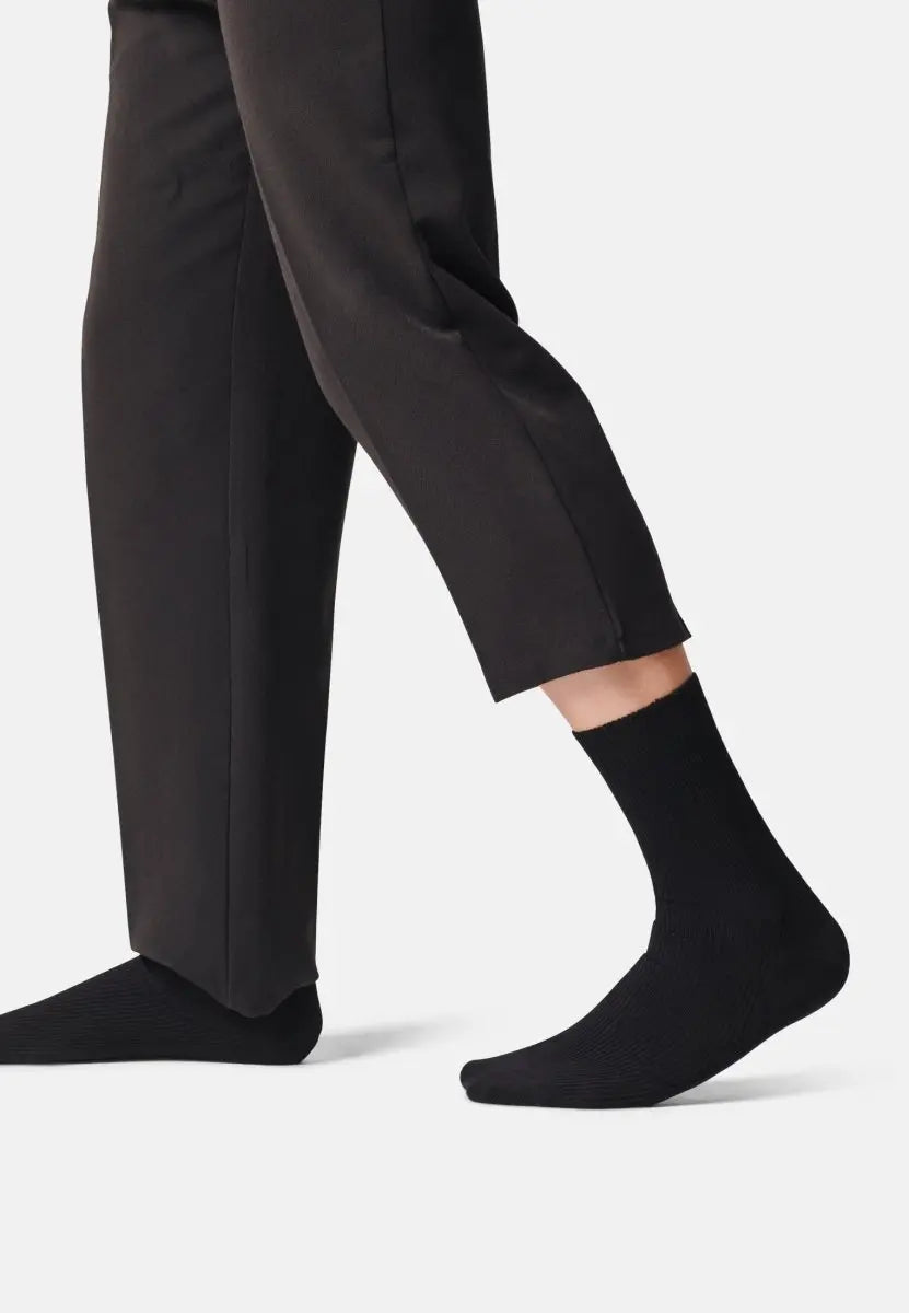 Person wearing black crew socks and black pants, highlighting the socks' soft texture and fit.