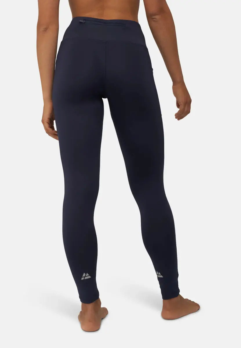 Woman wearing navy blue sport leggings, viewed from the back, standing barefoot on a light background.