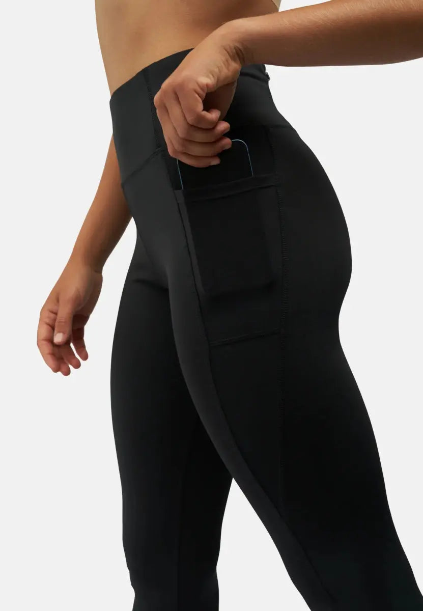 Woman wearing black leggings with a side pocket holding a phone.