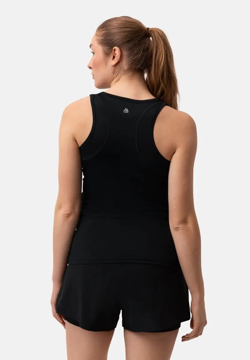 Woman in black tank top and shorts, back view, hair in ponytail, white background.