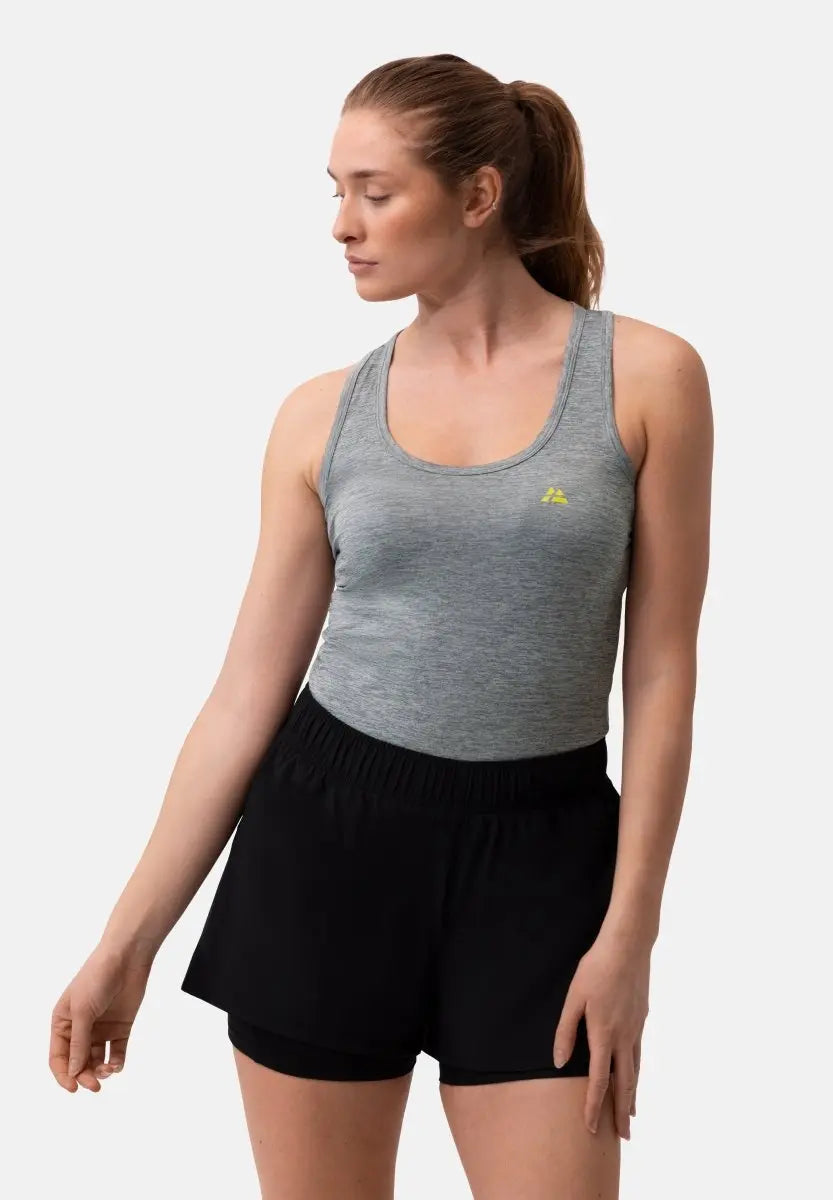Woman in gray tank top with yellow logo and black shorts, looking to the side.