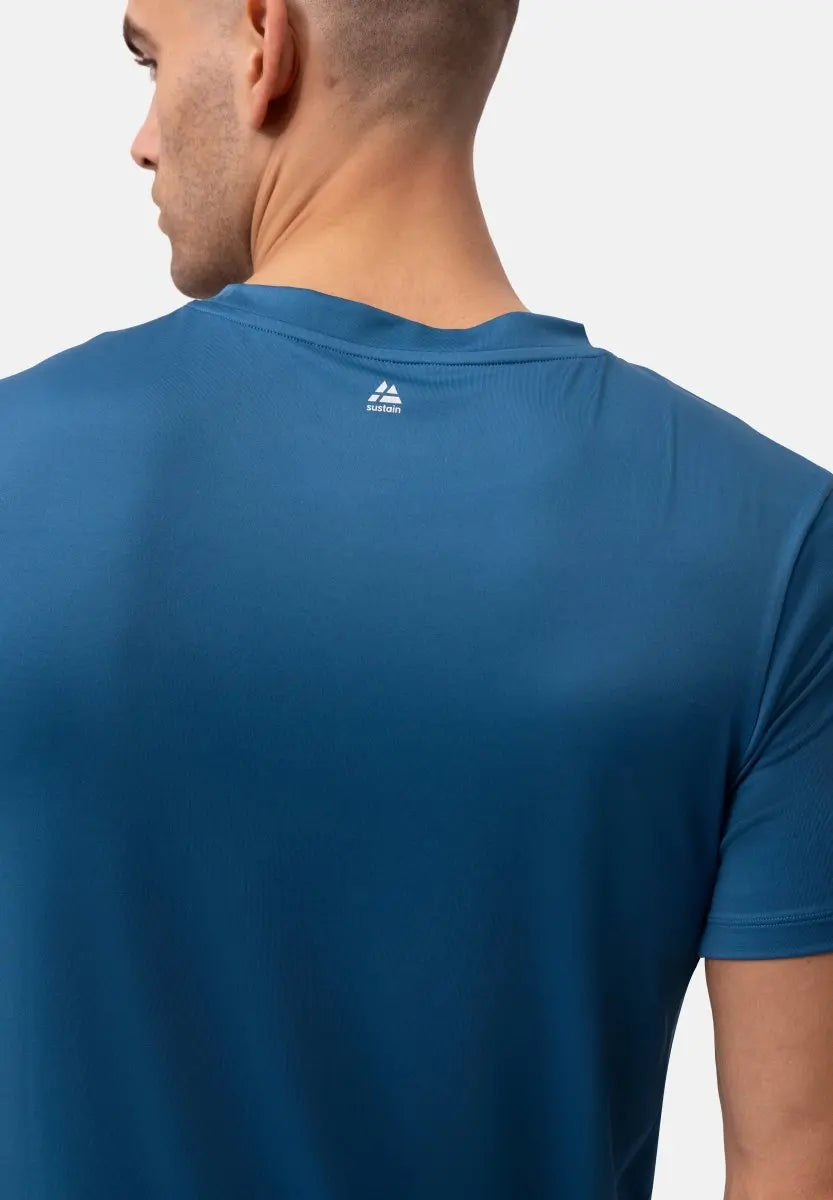 Man wearing a blue T-shirt, back view, with a small logo near the neck.