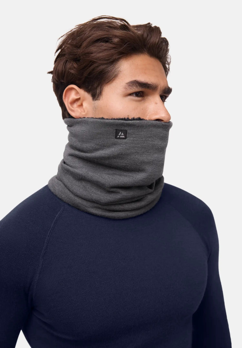 Person wearing a gray merino wool neck gaiter, covering neck and lower face, navy top visible.