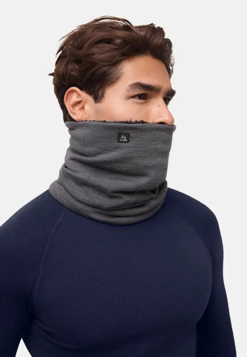 Person wearing a gray merino wool neck gaiter, covering neck and lower face, navy top visible.
