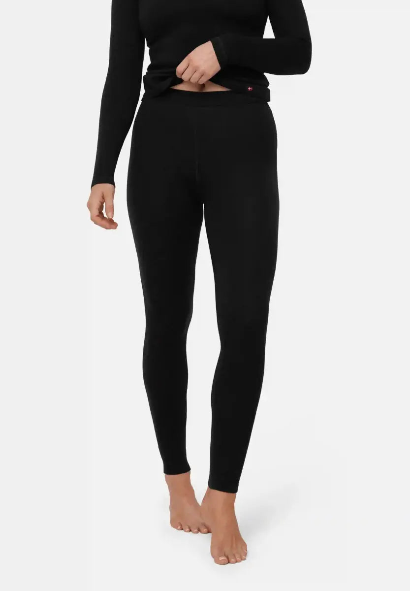 Person in black merino tights and top, barefoot, showing the fit and texture of the base layer.
