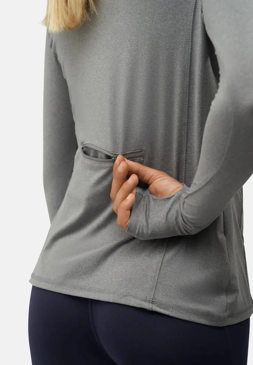 Woman wearing a gray long sleeve athletic shirt with a back zipper pocket.