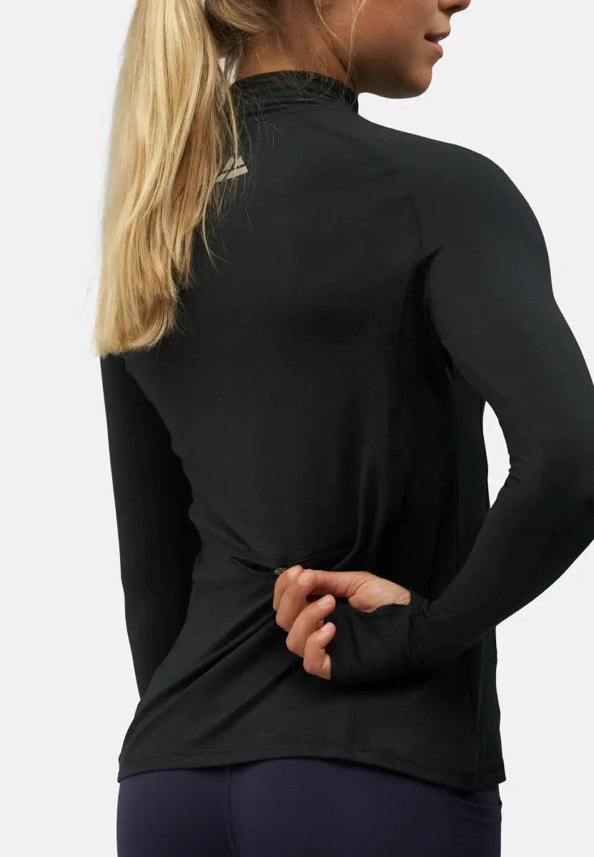 Woman wearing a black long sleeve athletic shirt with a back zipper pocket, holding the zipper.