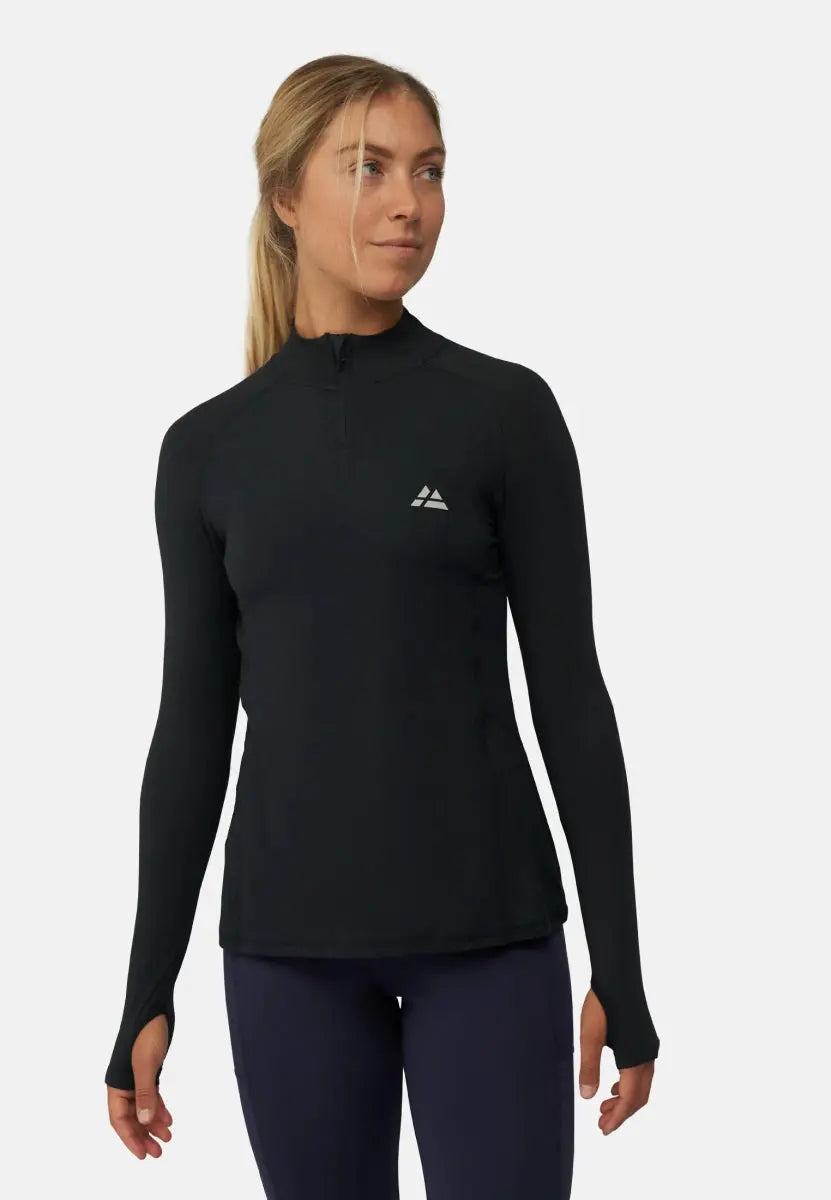Woman in black long sleeve athletic shirt with logo, standing against a plain background.