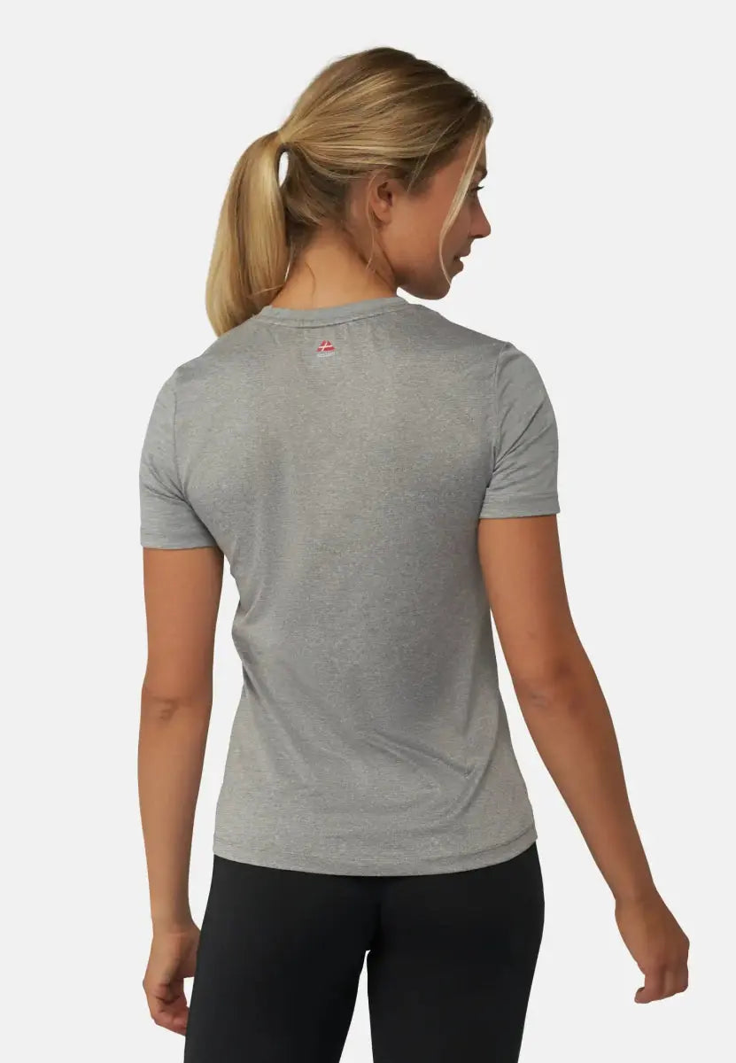 Woman in gray sports T-shirt and black leggings, hair in ponytail, shown from the back.