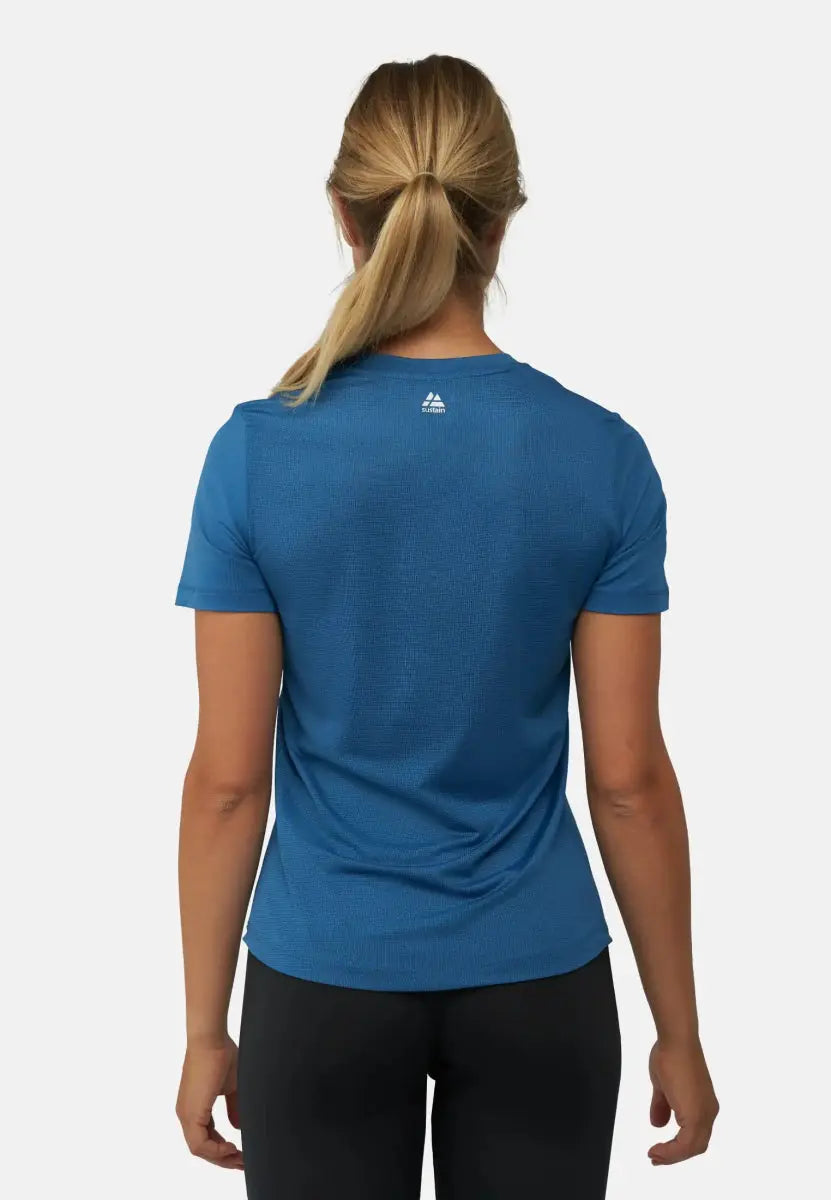 Back view of a woman in a blue sports T-shirt with a small logo near the collar.