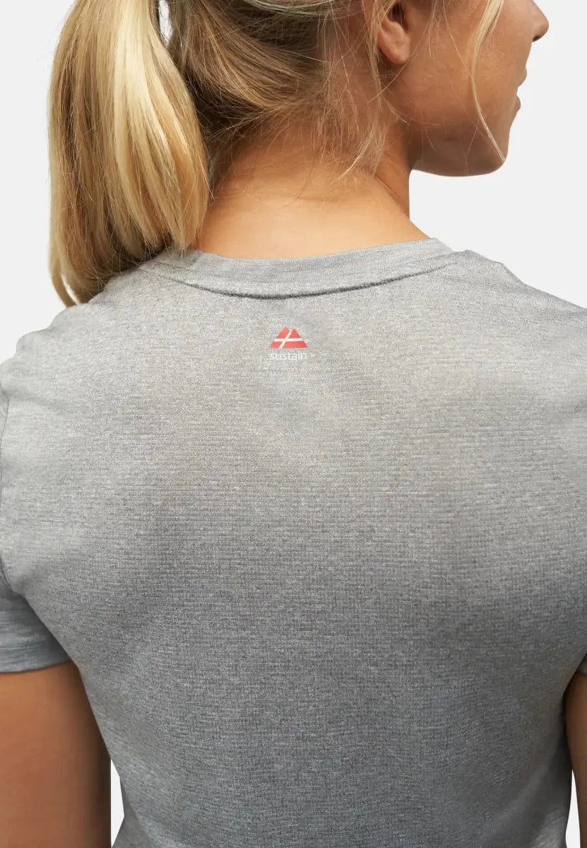 Back view of woman in gray sports T-shirt with red logo near neckline, hair in ponytail.
