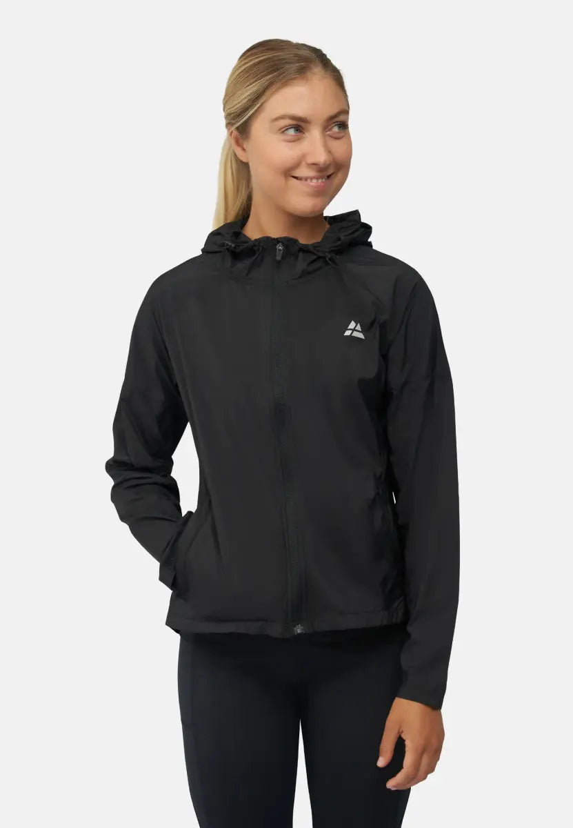 Woman wearing a black windbreaker jacket with a hood and chest logo, smiling to the side.