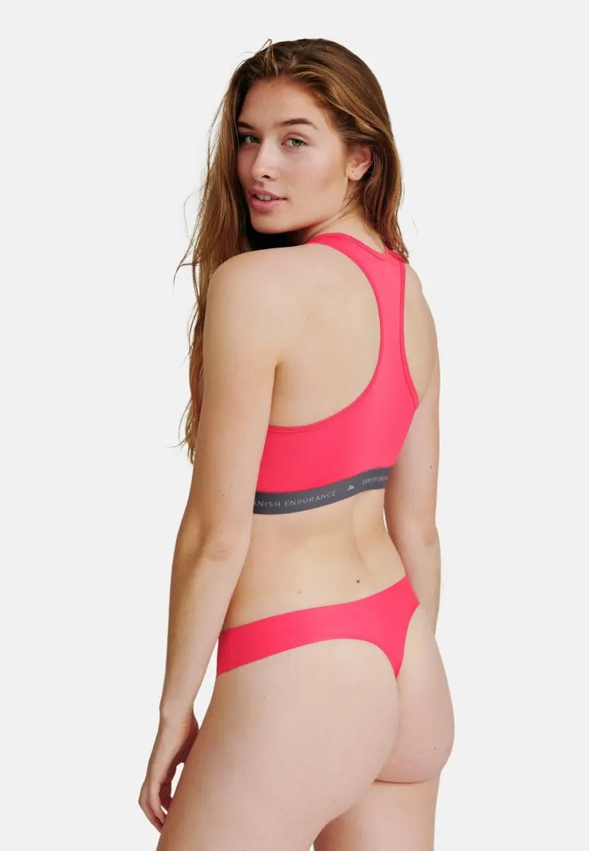 Woman in pink sports bra and thong, showing back view.