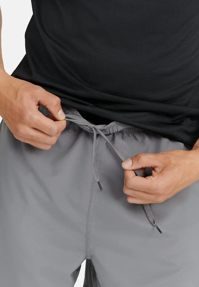 Hands adjusting drawstring on gray sport shorts, wearing a black shirt.