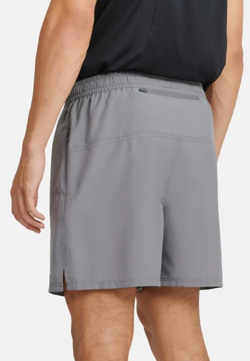 Gray sports shorts with elastic waist, rear pocket, and side slits, worn by a person from behind.