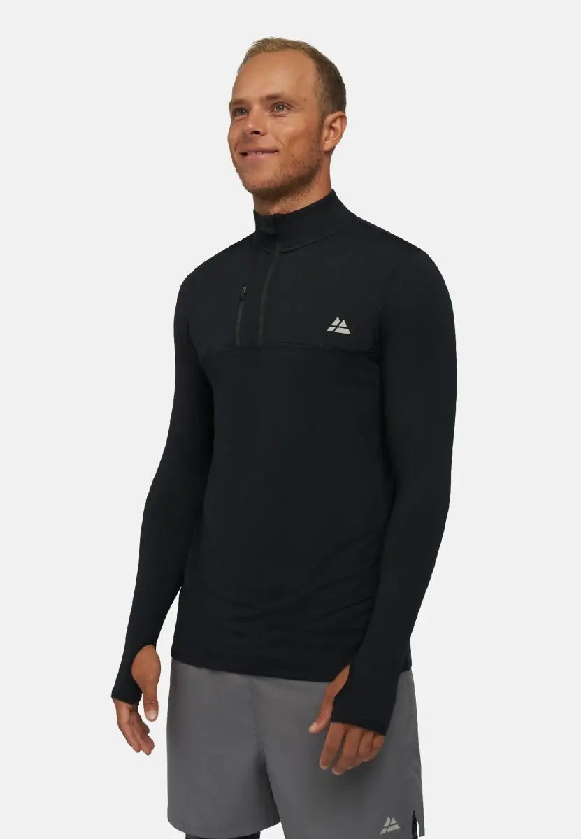 Man in a black long sleeve workout shirt with zippered collar and logo, wearing gray shorts.