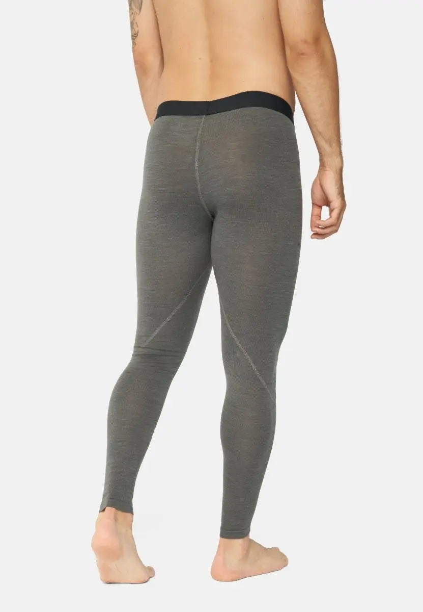 Man wearing gray merino wool base layer pants, black waistband, seen from the back, barefoot.