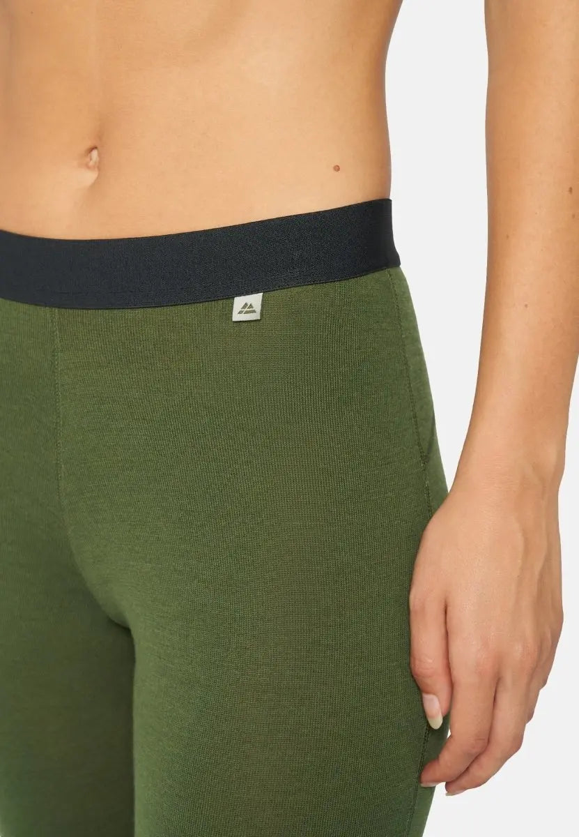 Close-up of green Merino wool pants with a black waistband on a person, showcasing fabric texture.